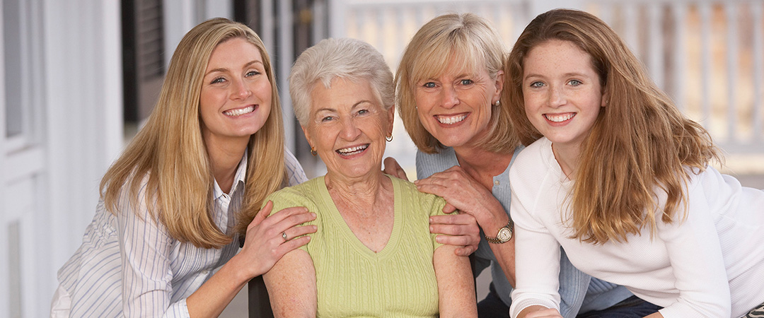 Group of four generations of women smiling.